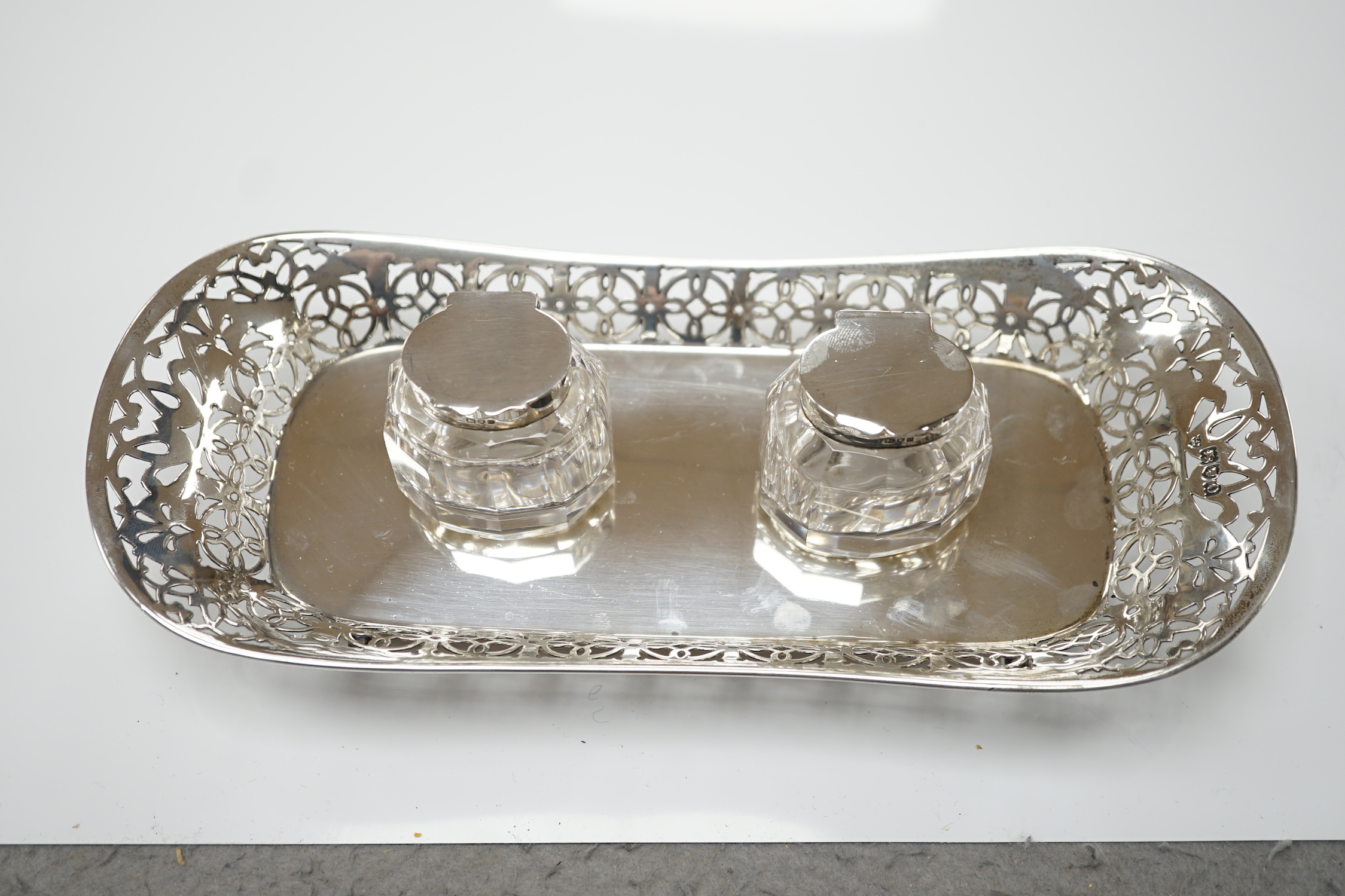 An Edwardian pierced silver inkstand, with two mounted glass wells, on four feet, Haseler Brothers, London, 1909, 26.2cm, 6.5oz.